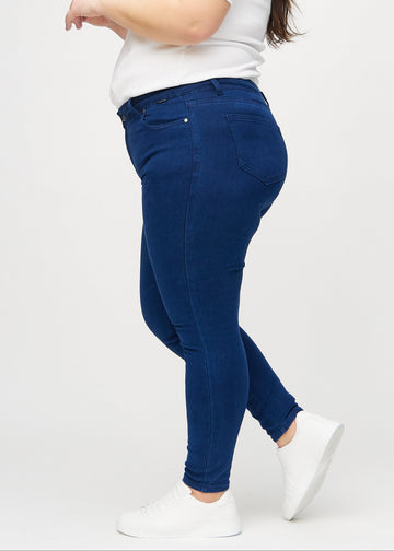Mørkeblå skinny jeans sett fra siden på en plus-size-modell.