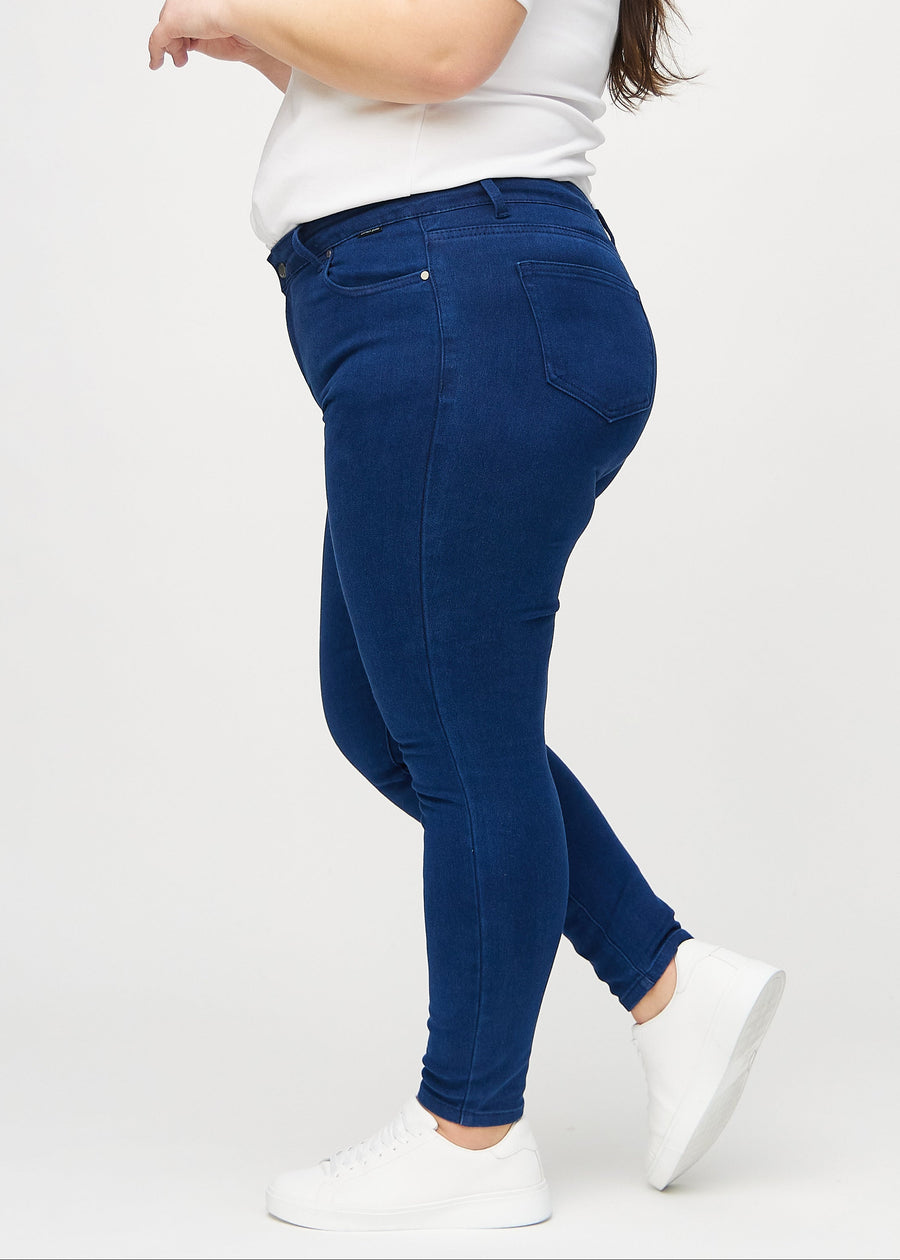 Mørkeblå skinny jeans sett fra siden på en plus-size-modell.