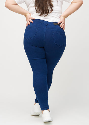 Mørkeblå skinny jeans sett bakfra på en plus-size-modell, så man kan se hele produktet.