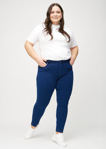 Fullt bilde av en plus-size-modell i mørkeblå skinny jeans.
