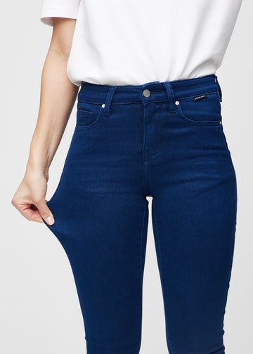 Modellen strekker jeansene ved låret for å vise stretch.