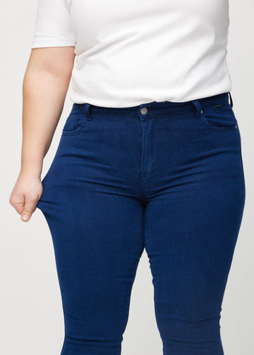 Plus-size-modellen strekker jeansene ved låret for å vise stretch.