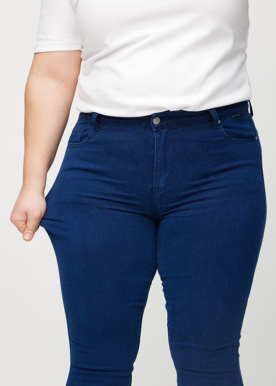 Plus-size-modellen strekker jeansene ved låret for å vise stretch.