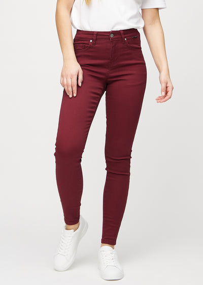 Skinny-jeans til kvinner i mørkerød, fargen Santas. Sett forfra på en modell, med tettsittende ben.