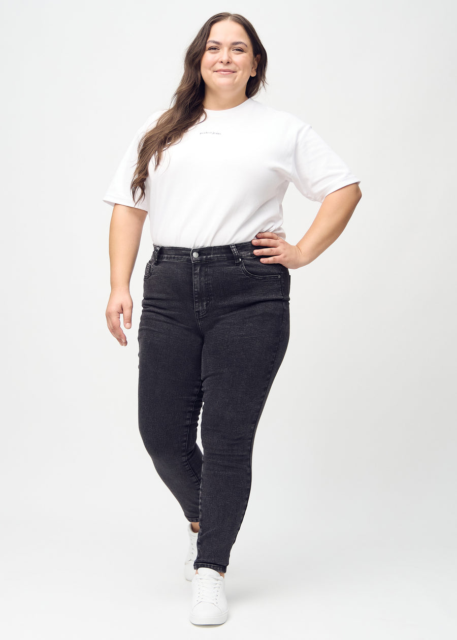Skinny-jeans til kvinner i mørkegrå, fargen Shadows. Helhetsbilde av en plus size-modell med jeansene på.