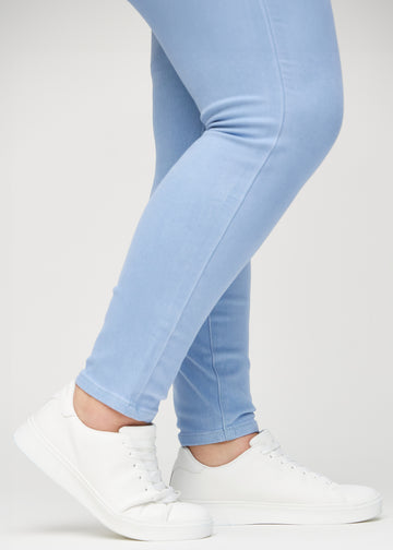 Skinny-jeans til kvinner i lyseblå, fargen Skies. Nærbilde ved anklene på en plus size-modell, som viser de tettsittende benåpningene.
