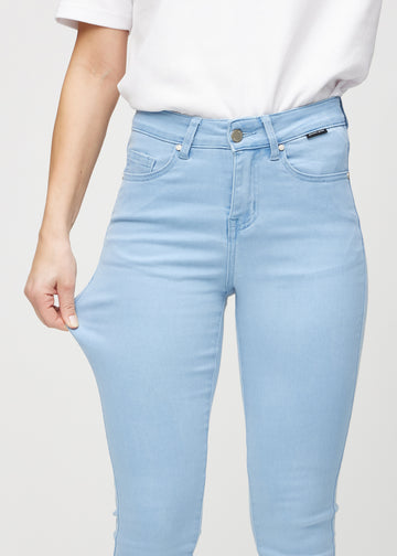 Skinny-jeans til kvinner i lyseblå, fargen Skies. En modell strekker jeansstoffet ved låret for å vise stretchen.