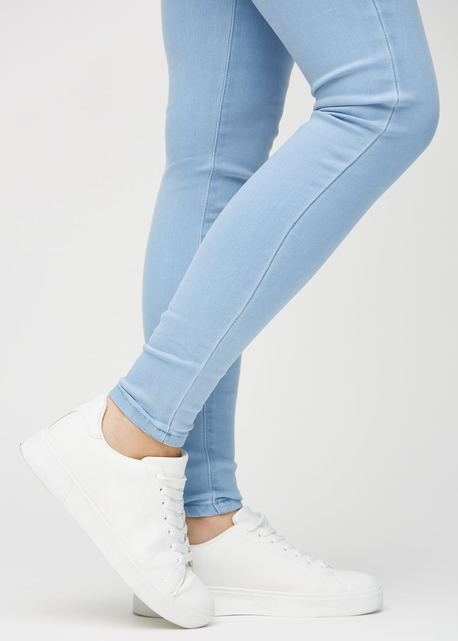 Skinny-jeans til kvinner i lyseblå, fargen Skies. Nærbilde ved anklene på en modell, som viser de tettsittende benåpningene.