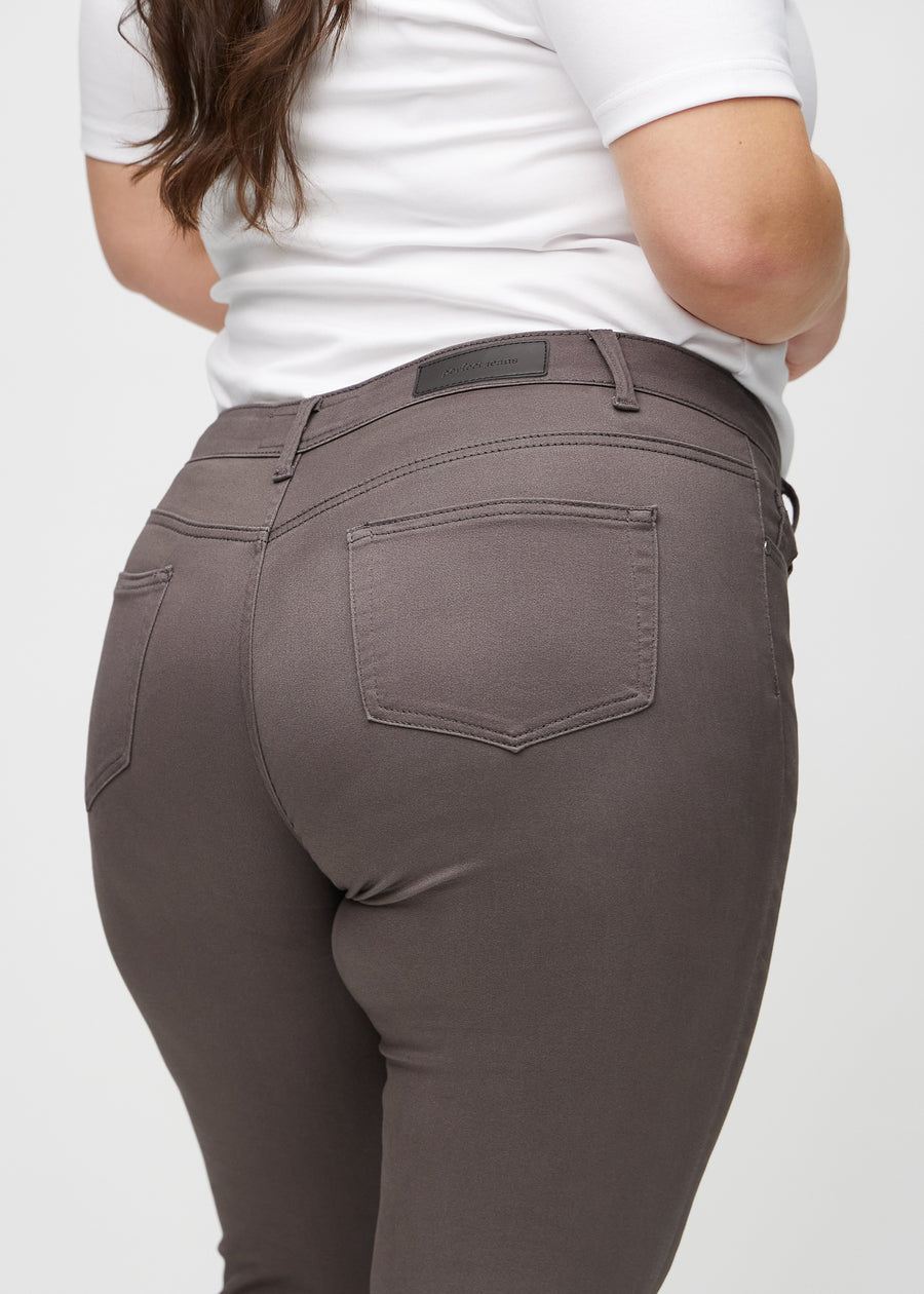 Skinny-jeans til kvinner i gråbrun, fargen Thunders. Nærbilde bakfra på en plus size-modell for å vise detaljer.