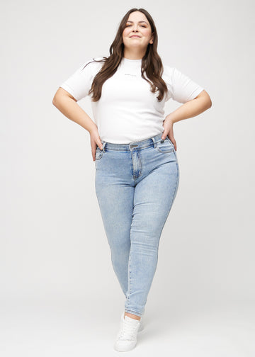 Skinny-jeans til kvinner i lyseblå, fargen Waves. Helhetsbilde av en plus size-modell med jeansene på.