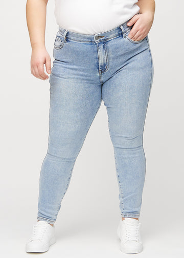 Skinny-jeans til kvinner i lyseblå, fargen Waves. Sett forfra på en plus size-modell, med tettsittende ben.
