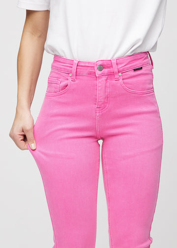 Slim-jeans til kvinner i lyserosa, fargen Flamingos. En modell strekker jeansstoffet ved låret for å vise stretchen.