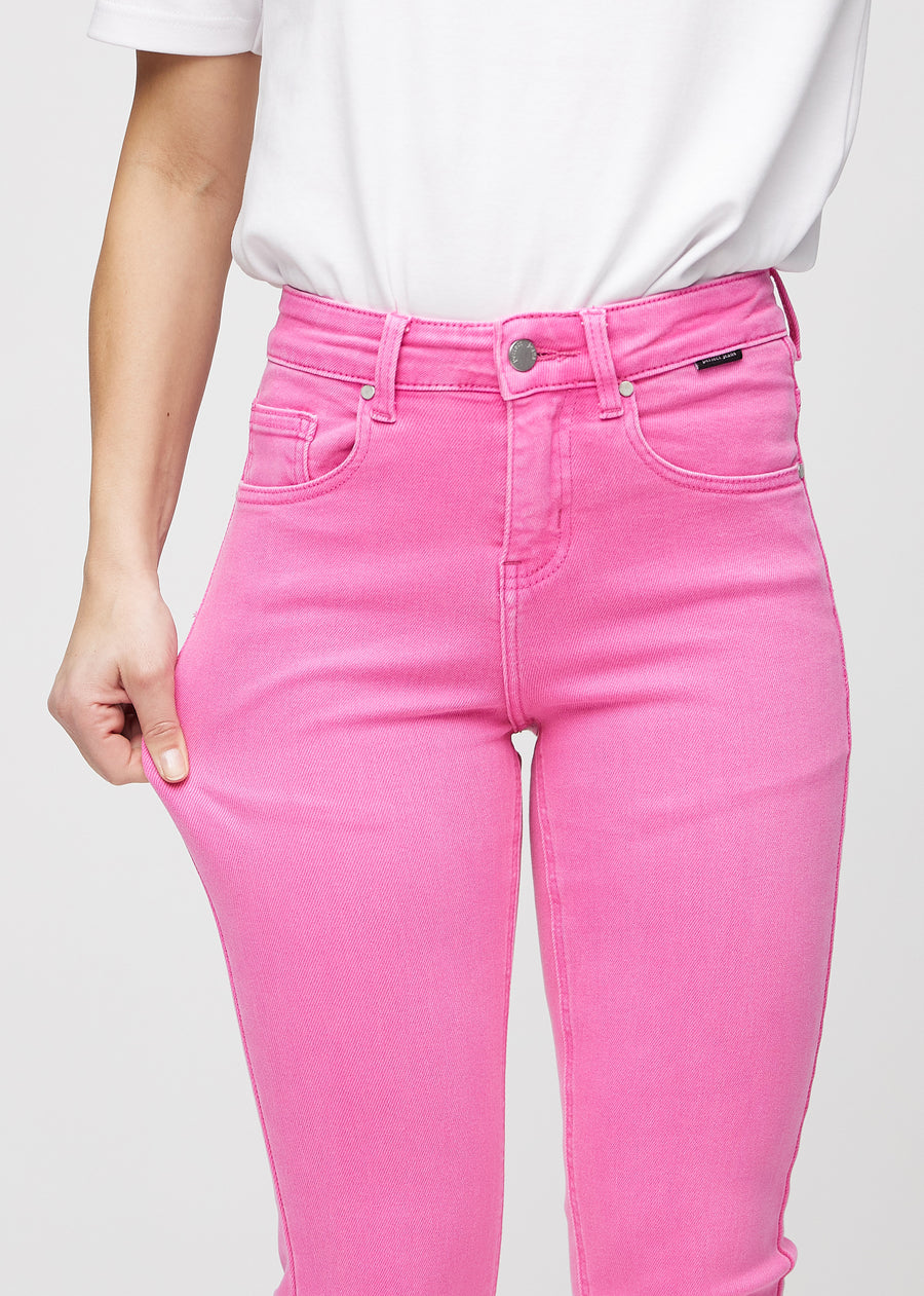 Slim-jeans til kvinner i lyserosa, fargen Flamingos. En modell strekker jeansstoffet ved låret for å vise stretchen.