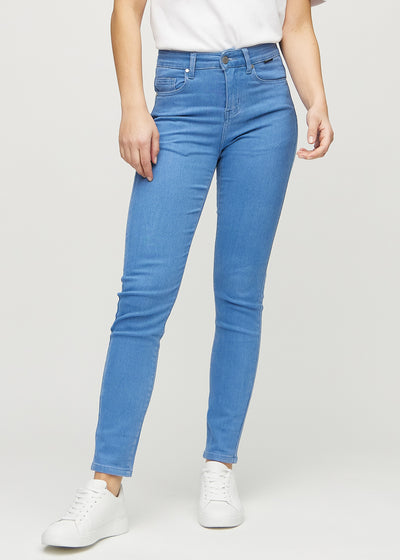 Slim-jeans til kvinner i blå, fargen Geraniums. Sett forfra på en modell, med tettsittende ben og litt mer plass ved anklene.