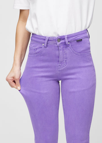 Slim-jeans til kvinner i lilla, fargen Lavenders. En modell strekker jeansstoffet ved låret for å vise stretchen.