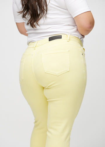 Slim-jeans til kvinner i lysegul, fargen Lemonades. Nærbilde bakfra på en plus size-modell for å vise detaljene.