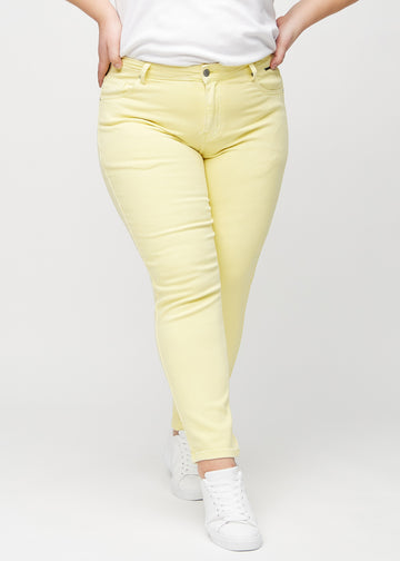 Slim-jeans til kvinner i lysegul, fargen Lemonades. Sett forfra på en plus size-modell, med tettsittende ben og litt mer plass ved anklene.