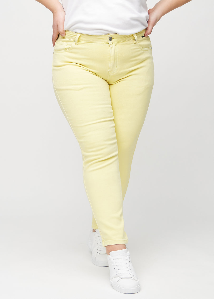 Slim-jeans til kvinner i lysegul, fargen Lemonades. Sett forfra på en plus size-modell, med tettsittende ben og litt mer plass ved anklene.