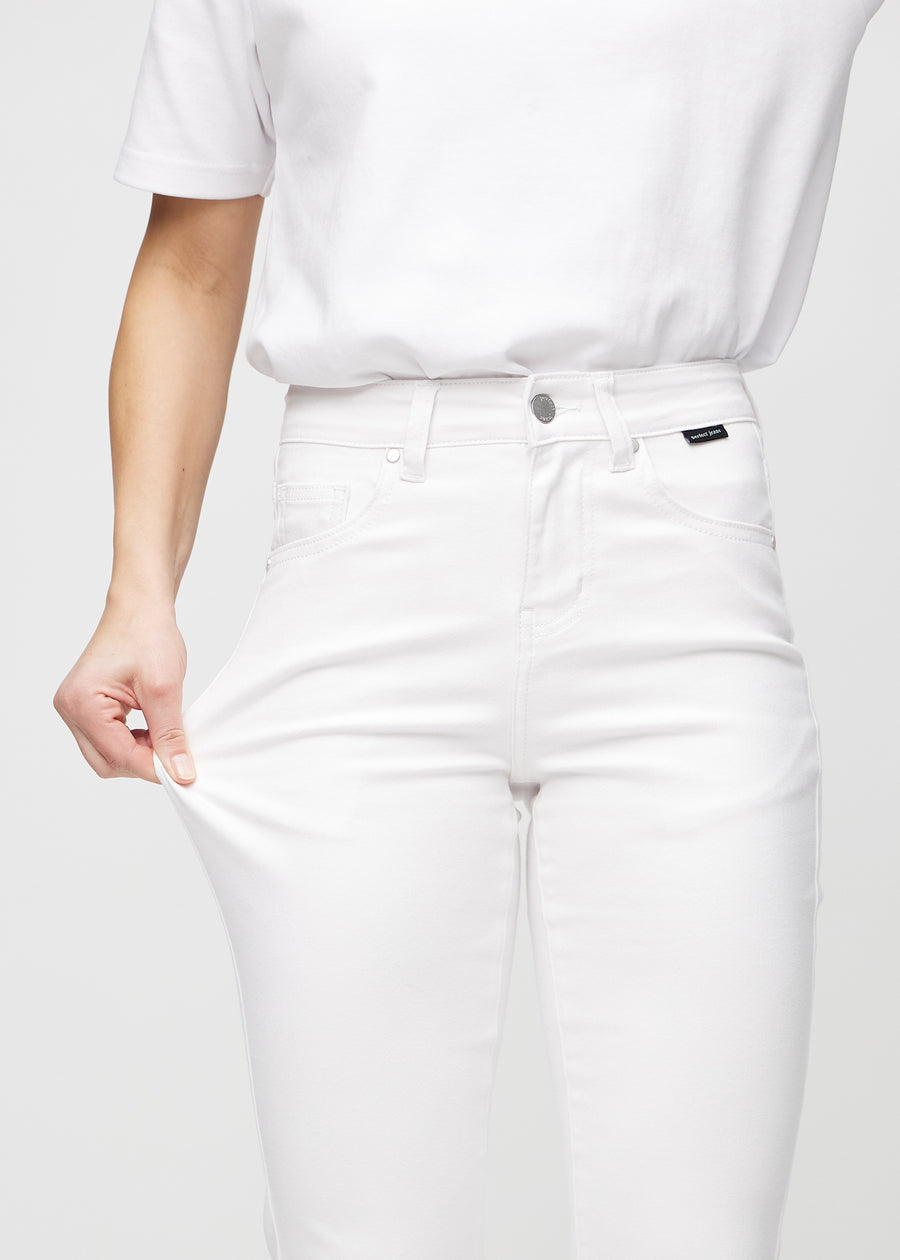 Slim-jeans til kvinner i hvit, fargen Marguerites. En modell strekker jeansstoffet ved låret for å vise stretchen.