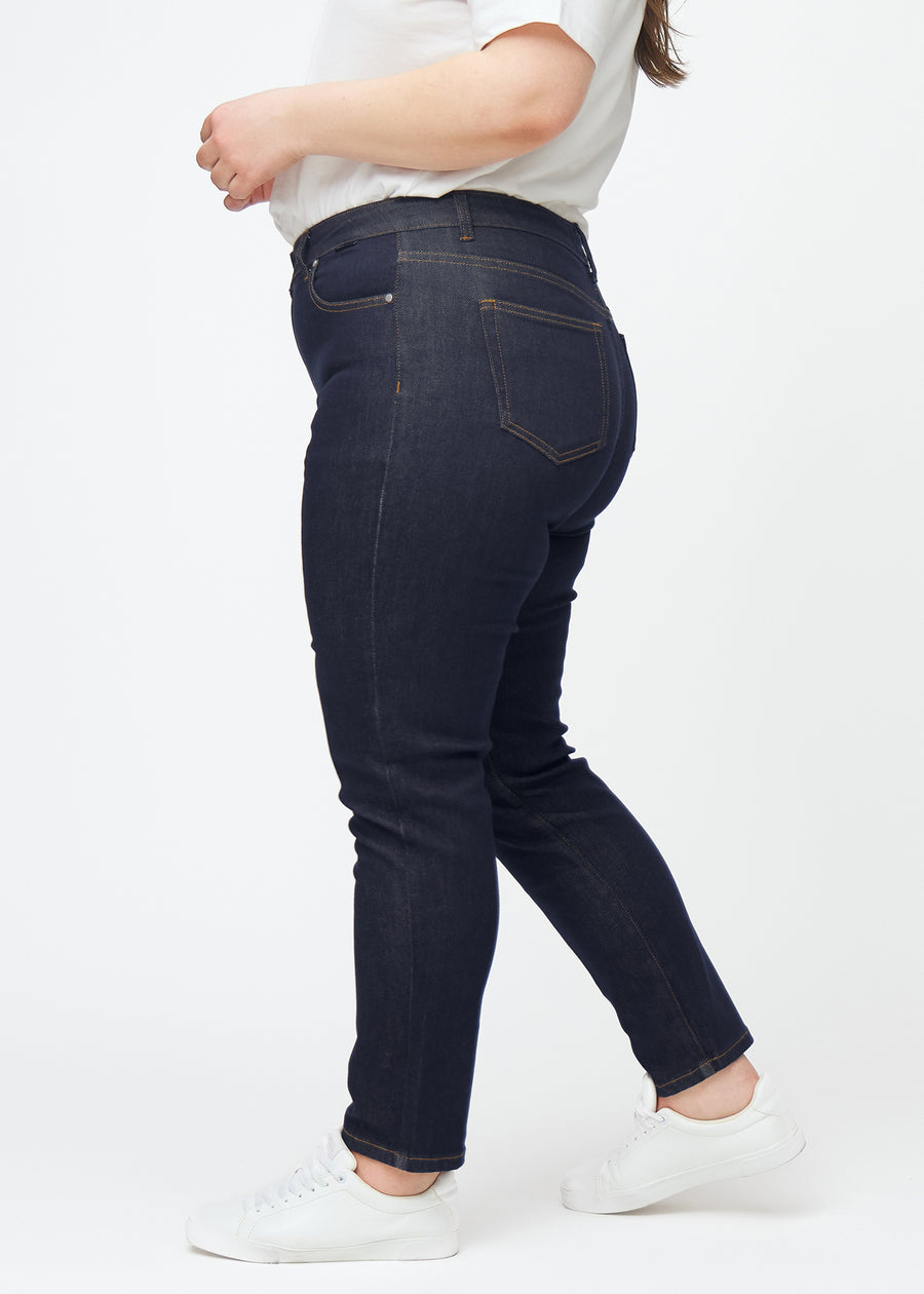 Dyp mørkeblå denim jeans til kvinner i fargen Midnights med slim passform sett fra siden på plus-size-modell.