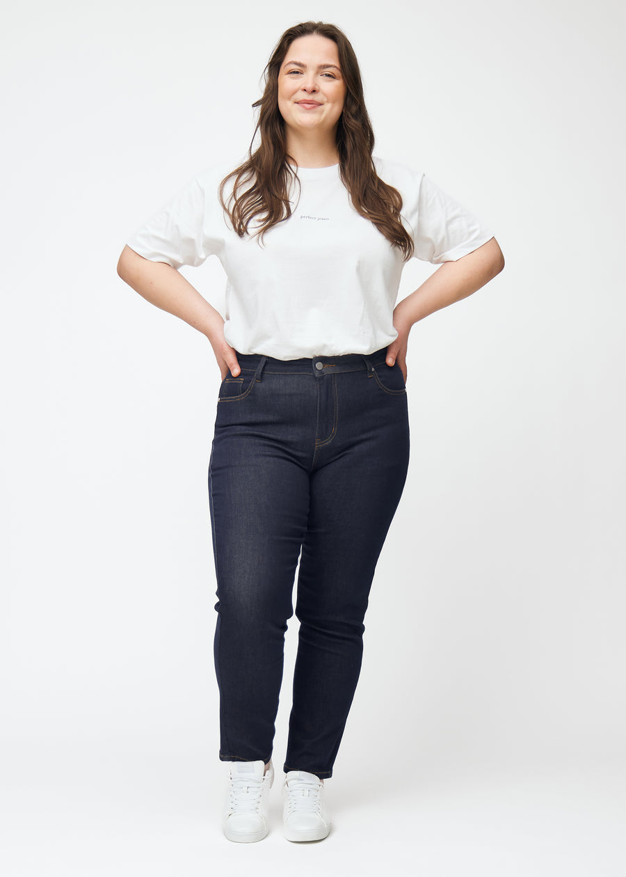 Fullt bilde av plus-size-modell i dyp mørkeblå denim jeans til kvinner i fargen Midnights med slim passform.