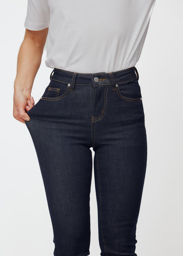 Modell strekker dyp mørkeblå denim jeans til kvinner i fargen Midnights ved låret for å vise materialets stretch.