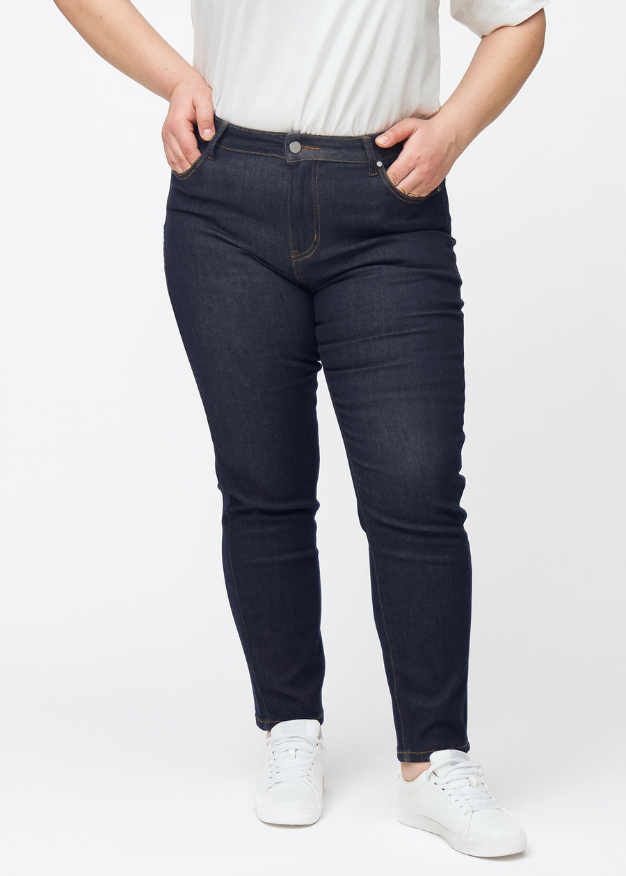 Dyp mørkeblå denim jeans til kvinner i fargen Midnights med slim passform sett forfra på plus-size-modell.