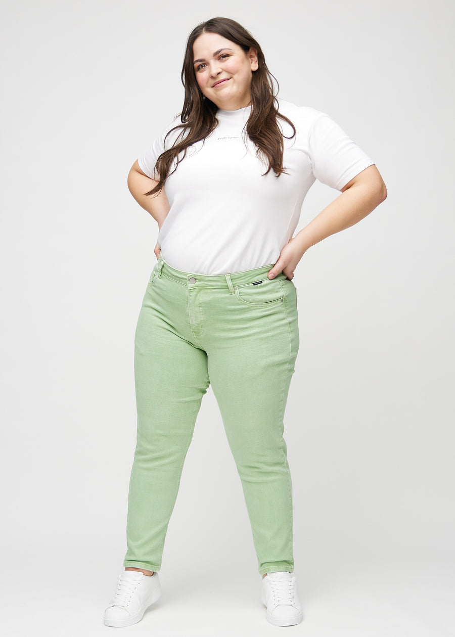 Fullt bilde av en plus-size modell i lysegrønne slim jeans.