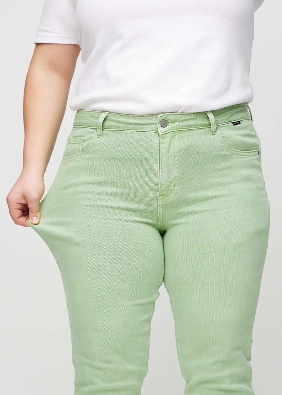 Plus-size modell strekker jeansene ved låret for å vise stretch.