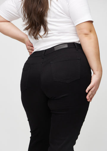 Svarte slim jeans sett bakfra på nært hold på en plus-size-modell for å vise detaljer.