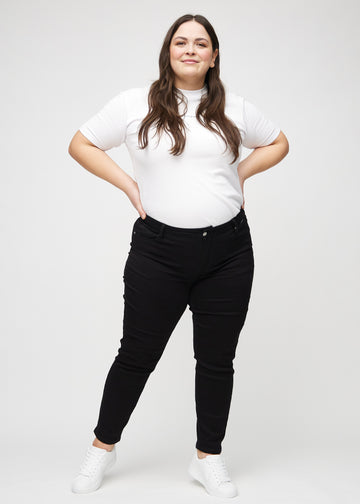 Fullt bilde av en plus-size-modell i svarte slim jeans.