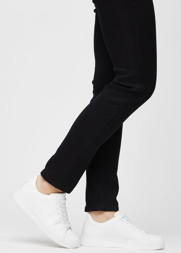 Anklene på en modell, så man kan se hvor tett jeansene sitter i en Slim passform.