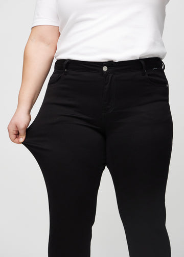 Plus-size-modellen strekker jeansene ved låret for å vise stretch.