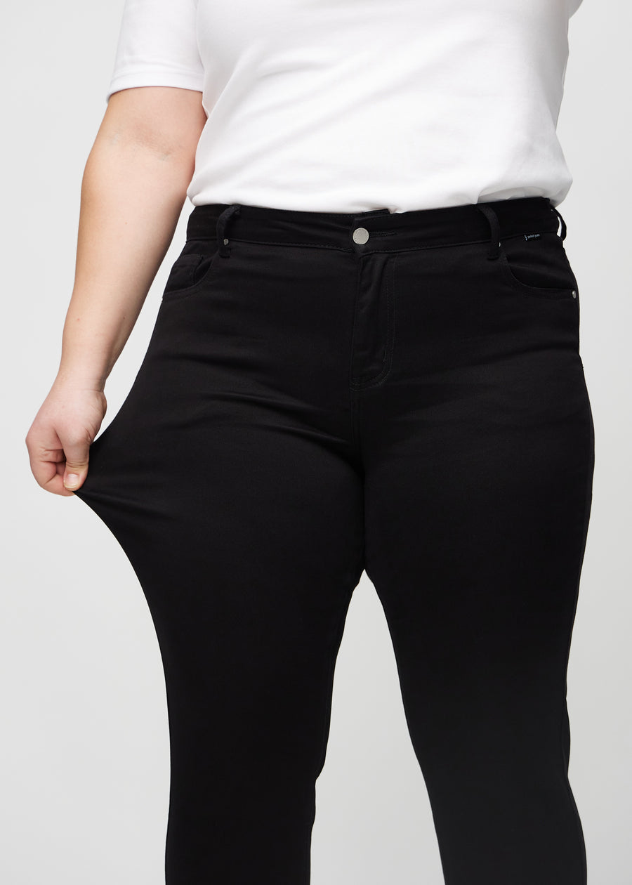Plus-size-modellen strekker jeansene ved låret for å vise stretch.