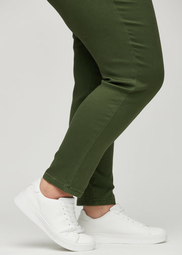 Slim-jeans til kvinner i mørkegrønn, fargen Renewals. Nærbilde ved anklene på en plus size-modell, som viser passformen nederst på bena.