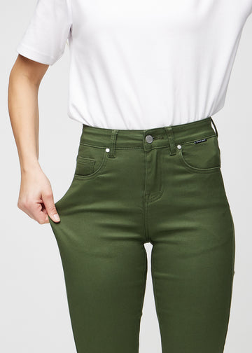 Slim-jeans til kvinner i mørkegrønn, fargen Renewals. En modell strekker jeansstoffet ved låret for å vise stretchen.