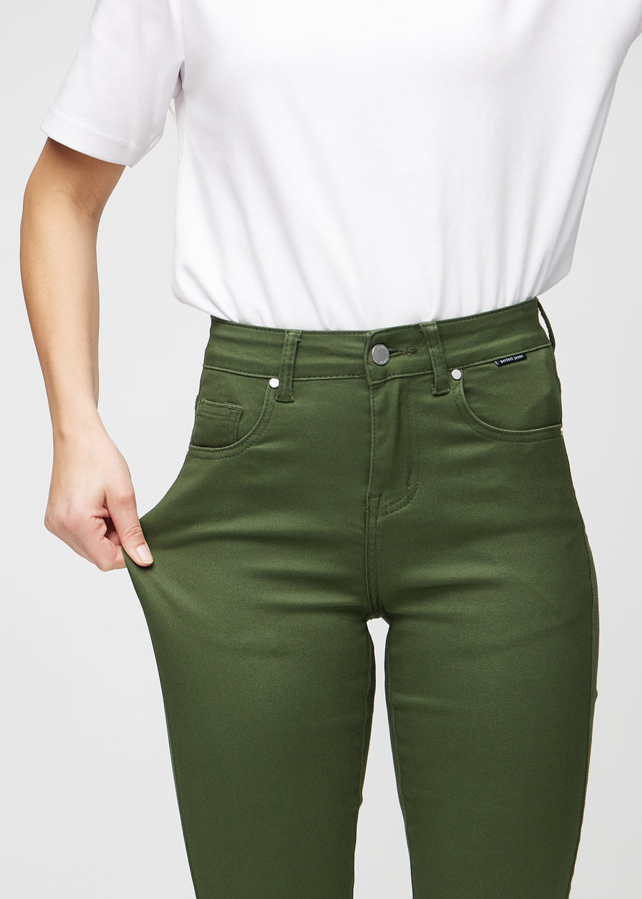 Slim-jeans til kvinner i mørkegrønn, fargen Renewals. En modell strekker jeansstoffet ved låret for å vise stretchen.