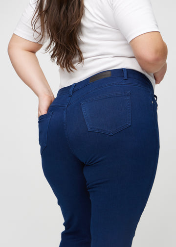 Slim-jeans til kvinner i mørkeblå, fargen Royals. Nærbilde bakfra på en plus size-modell for å vise detaljene.