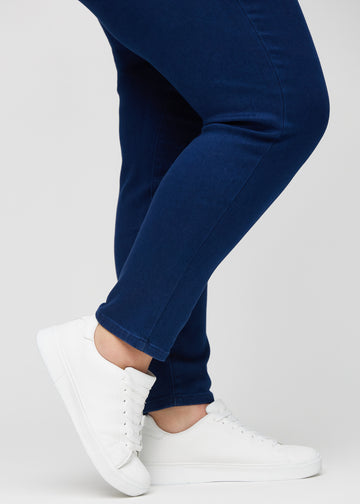 Slim-jeans til kvinner i mørkeblå, fargen Royals. Nærbilde ved anklene på en plus size-modell, som viser passformen nederst på bena.
