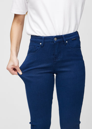 Slim-jeans til kvinner i mørkeblå, fargen Royals. En modell strekker jeansstoffet ved låret for å vise stretchen.