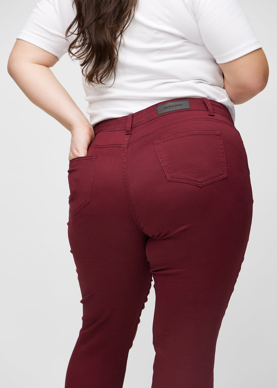 Slim-jeans til kvinner i mørkerød, fargen Santas. Nærbilde bakfra på en plus size-modell for å vise detaljene.