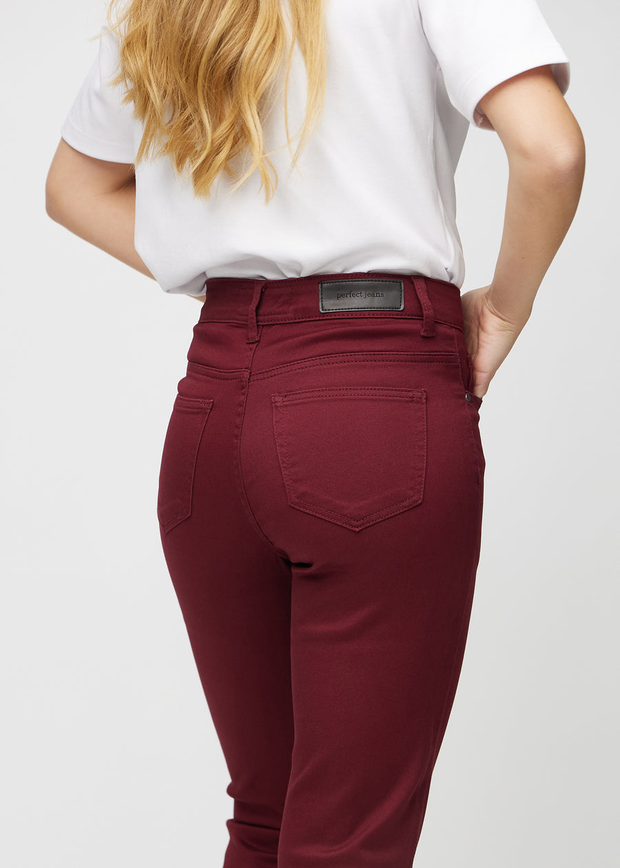 Slim-jeans til kvinner i mørkerød, fargen Santas. Nærbilde bakfra på en modell for å vise detaljene.