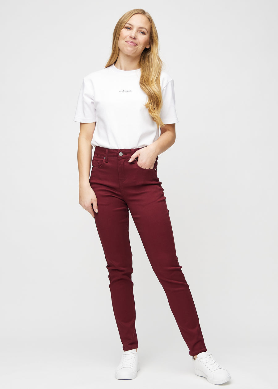 Slim-jeans til kvinner i mørkerød, fargen Santas. Helhetsbilde av en modell med jeansen på.