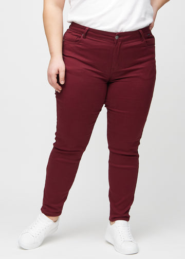 Slim-jeans til kvinner i mørkerød, fargen Santas. Sett forfra på en plus size-modell, med tettsittende ben og litt mer plass ved anklene.