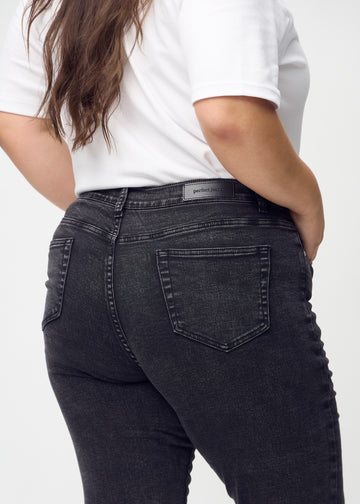 Slim-jeans til kvinner i mørkegrå, fargen Shadows. Nærbilde bakfra på en plus size-modell for å vise detaljene.