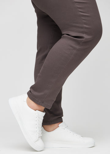 Slim-jeans til kvinner i gråbrun, fargen Thunders. Nærbilde ved anklene på en plus size-modell, som viser passformen nederst på bena.