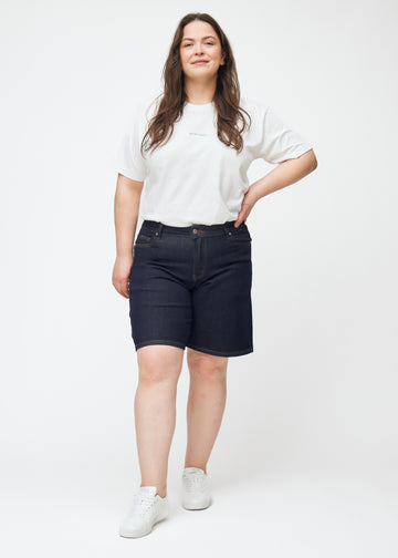 Helbilde av plus-size modell i dyp mørkeblå denimshorts til dame i fargen Midnights med loose passform.