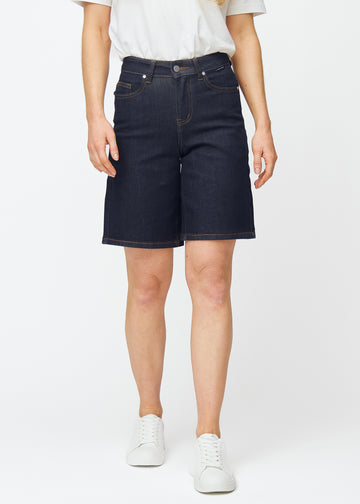 Dyp mørkeblå denimshorts til dame i fargen Midnights med loose passform som sitter ved hoften og faller løst over lårene, sett forfra.