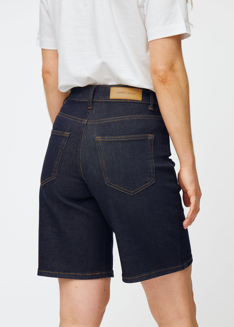 Dyp mørkeblå denimshorts til dame i fargen Midnights sett bakfra i nærbilde for å vise passform og detaljer.