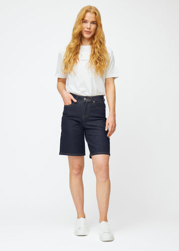 Helbilde av modell i dyp mørkeblå denimshorts til dame i fargen Midnights med loose passform.